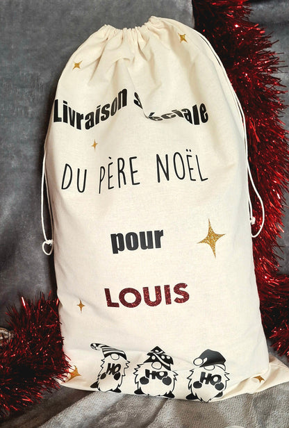 Hotte de Noël personnalisée déposée sous le sapin – ambiance magique et chaleureuse